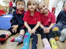 Three  sitting on the floor with legs stretched out to show their mismatching socks